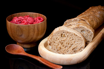 Composition on black background. Wooden plate with sliced bread,