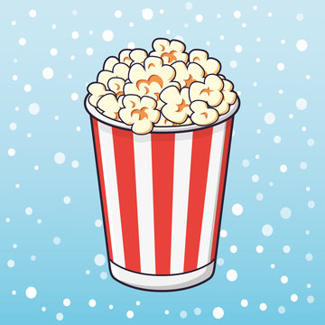 Popcorn in a red striped bucket on a snow background.