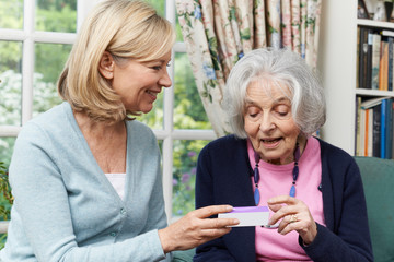 Fototapeta na wymiar Female Neighbor Helping Senior Woman With Medication