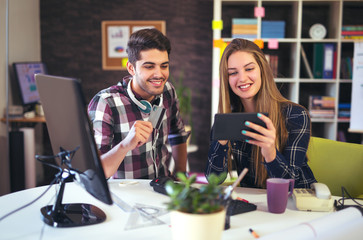 Couple of web designers working together at modern office, using credit card
