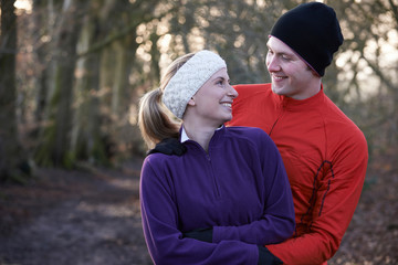 Young Couple On Winter Run Through Woodland