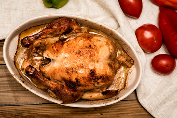 roasted chicken with a golden crust with vegetables on a wooden table