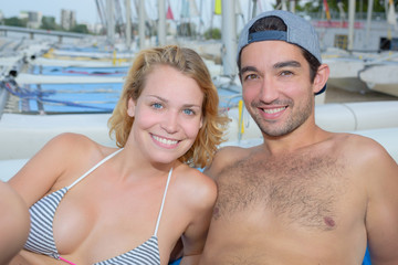 cheerful couple laying next to sailboats