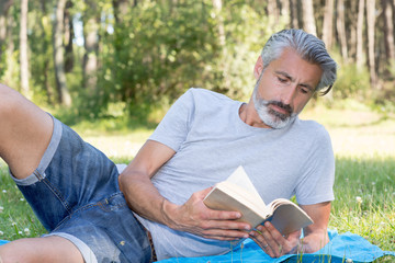 man lyingsitting in the grass reading a book