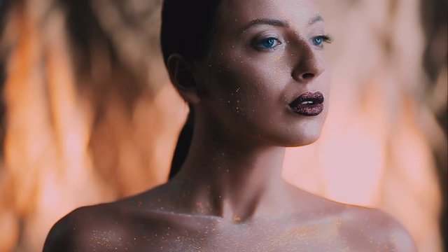 The girl's face is covered with gloss and glitter . Posing