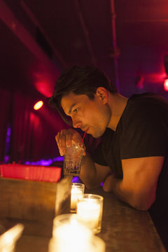Young man enjoying drink while sitting at bar