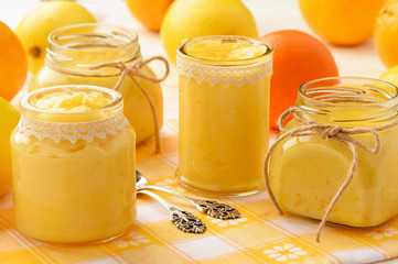 Orange curd and lemon curd  (english citrus cream) in glass jars.