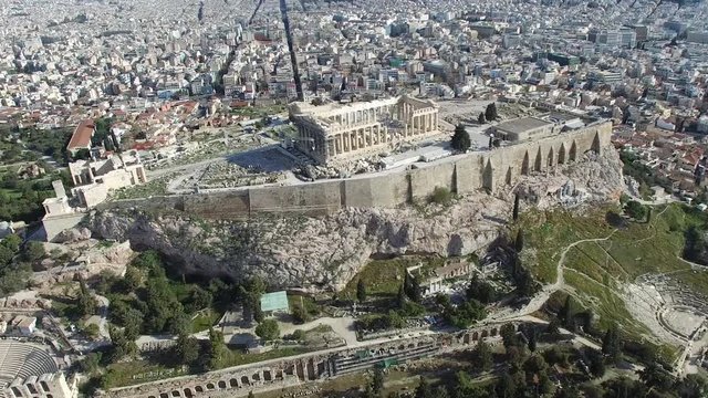 Aerial flying around the Acropolis of Athens ancient citadel located on rocky outcrop showing Parthenon very famous tourist attraction in Europe Greece European visit furthermore showing downtown 4k