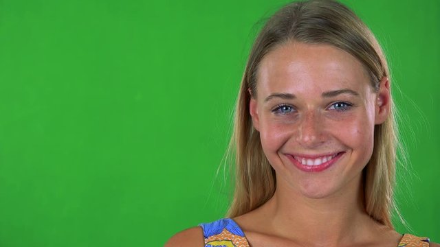 young pretty blond woman smiles to camera - green screen - studio 