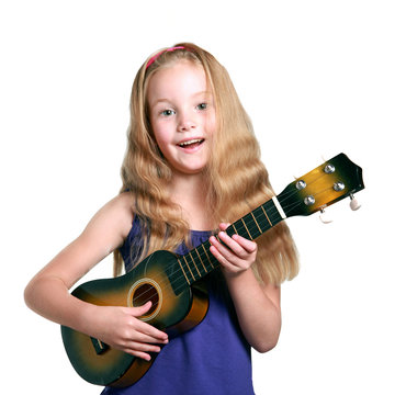 little blond girl in purple dress plays ukulele
