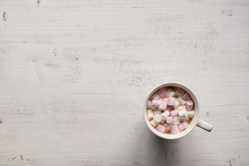 Hot chocolate with marshmallows on the white wooden table, top view