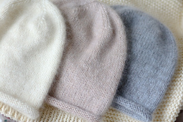 Three hats of the same style in blue, beige and white made of wool on the spokes