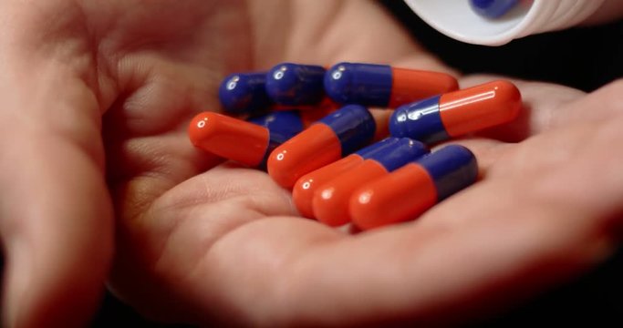 Blue-orange pills on open palm of woman