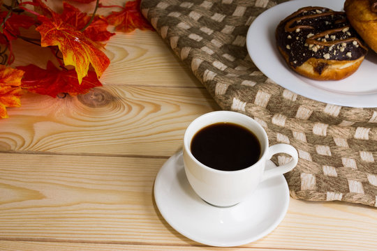 A cup of coffee with a chocolate donuts and autumn leaves
