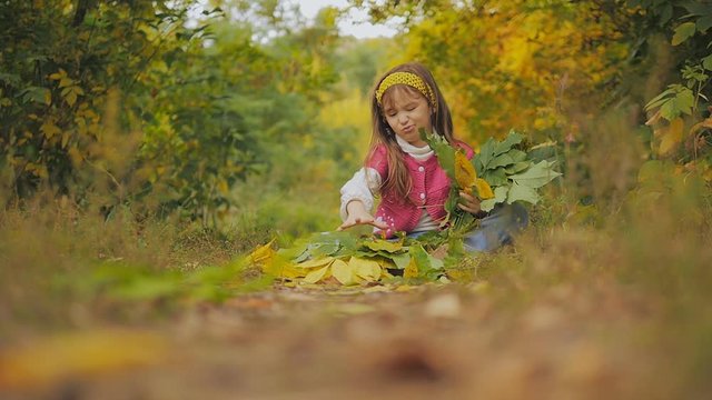 little girl throws autumn leaves. Happy child. Slow-motion