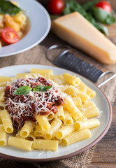 Pasta with tomato sauce and parmigiano on natural wooden table.