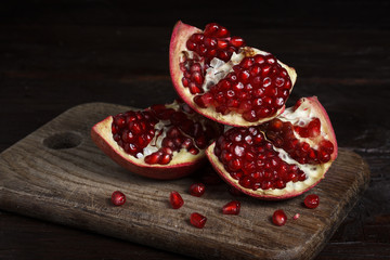 cut part of pomegranate on a wooden board on a wooden background.