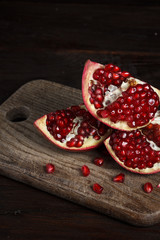 cut part of pomegranate on a wooden board on a wooden background.