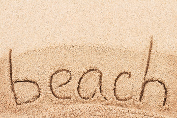 Beach - word handwritten on sand, background
