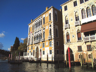 Beautiful traditional architecture with colorful mooring poles against vivid blue sky of Venice, Italy 