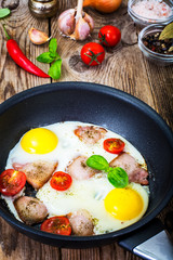 Fried eggs with bacon and tomatoes in a pan