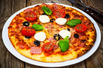 Italian pizza with ham, cheese, mushrooms, tomatoes and mozzarel