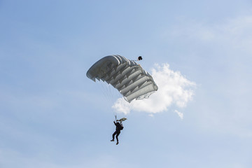 Parachutist with parachute is flying in the blue sky