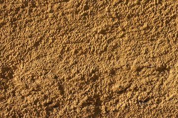 Ocher house rough plastered facade wall closeup as background