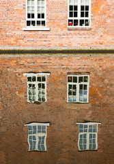 Abstract water reflections of old red brick buildings with windows in canal on a sunny day in England UK