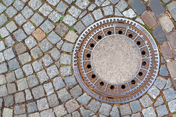 Manhole cover on pavement with patterns, Amsterdam