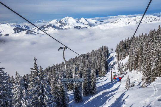 Skiers on ski lift enjoying the view to Tyrolian Alps in Kitzbühel ski resort, Austria