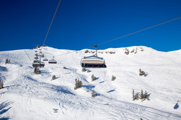 Fototapeta na wymiar Skiers on chair lift in Kitzbühel ski resort, Tyrolian Alps, Austria