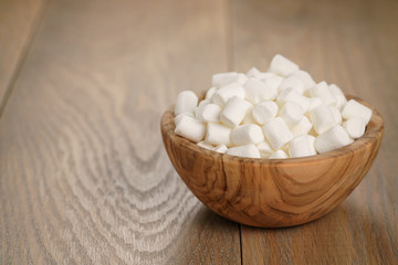 Fototapeta na wymiar white marshmallows in wooden bowl on table
