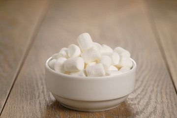 Fototapeta na wymiar white marshmallows in white bowl on table