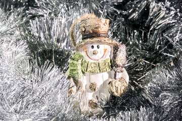 Carved old fashioned snowman smiling amidst silver tinsel