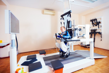 young boy passes robotic gait therapy in rehabilitation center