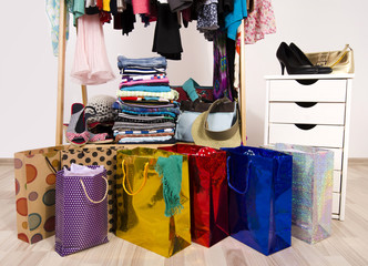 Wardrobe with clothes and shopping bags, on line shopping.Close up on many full bags in a woman closet.