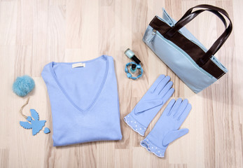 Winter sweater and accessories arranged on the floor.Woman blue and brown accessories,necklace and gloves lied down.