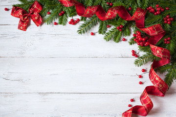 Christmas wooden background with branches of fir, red berries and ribbon
