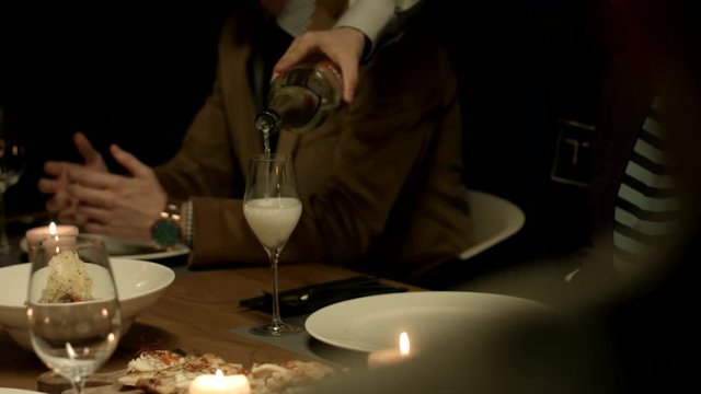 Waiter pours wine to a guest at a restaurant. 
