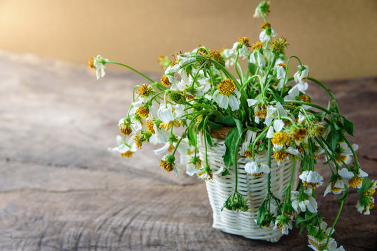 white flowers in basket on wooden table with brown paper background