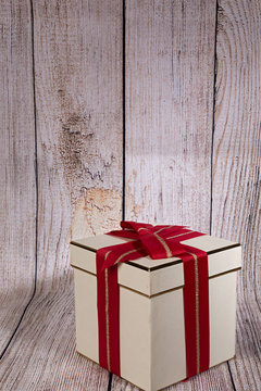 Caja para regalo con lazo rojo sobre fondo de madera.