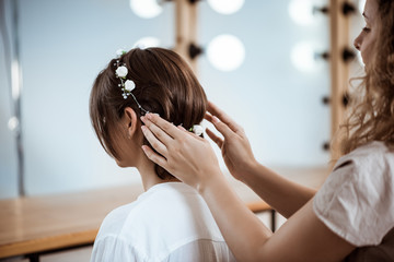 Naklejka premium Female hairdresser making hairstyle to brunette girl in beauty salon.