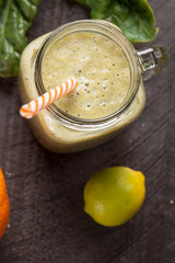 Freshly made glass of lime orange banana spinach green smoothie top view