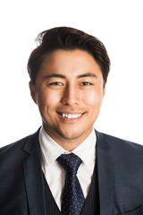 Handsome and well dressed businessman in a suit, tie and vest, standing against a white background smiling towards camera.
