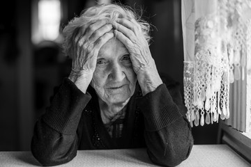 An elderly woman sitting at a table in a depressed state.