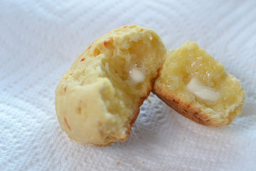 Brazilian cheese bread (Pao de queijo) cut in half served with butter over white paper towel