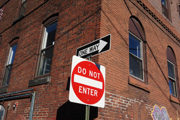 do not enter sign and one way sign near brick wall building in the city