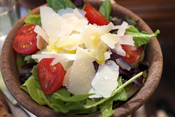 salade verte, tomates et parmesan dans un bol en bois.