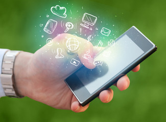 Hand holding smartphone with media icons